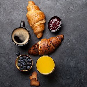 Desayuno con café, jugo de naranja, arándanos y croissant.
